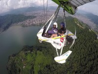 Pilot flying  ultralight flight over Phewa Lake with mountains in the background