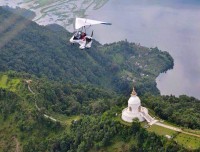 Person flying an ultralight aircraft over a scenic landscape of pokhara